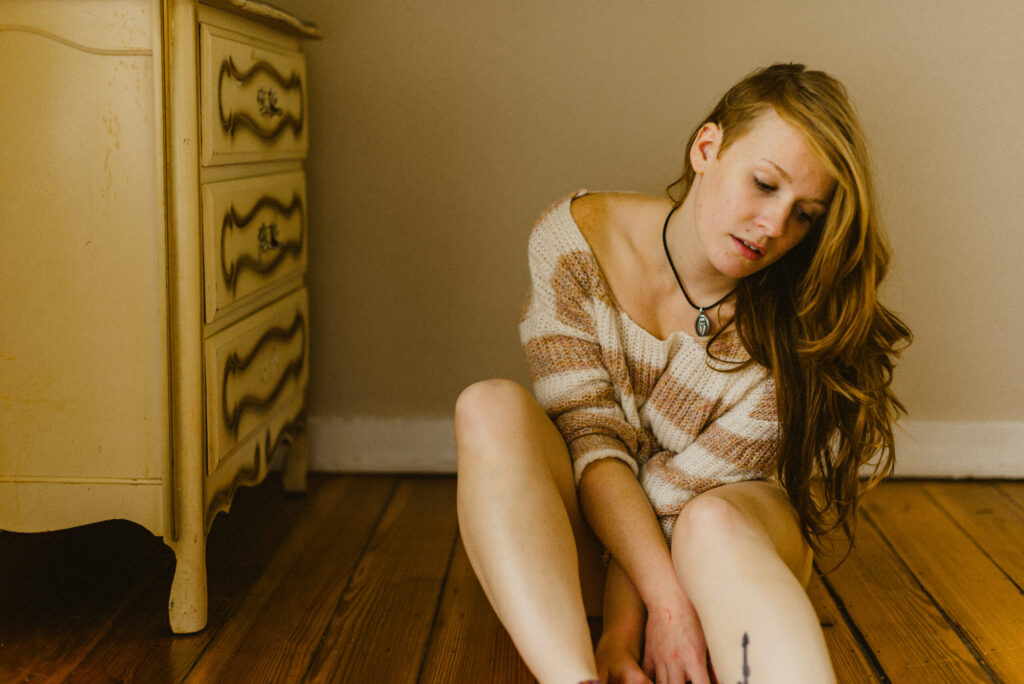 Woman sitting on wooden floor indoors.