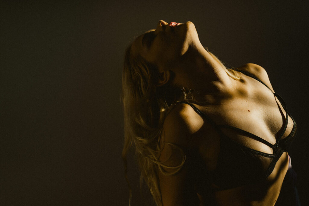 Woman in dramatic lighting, wearing a bra.