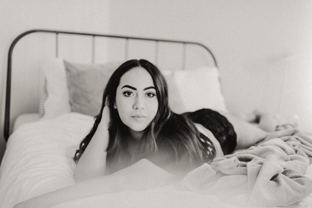 Woman lounging on bed, monochrome photography.