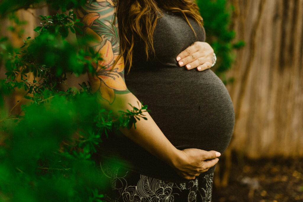 Pregnant woman with floral tattoo in garden