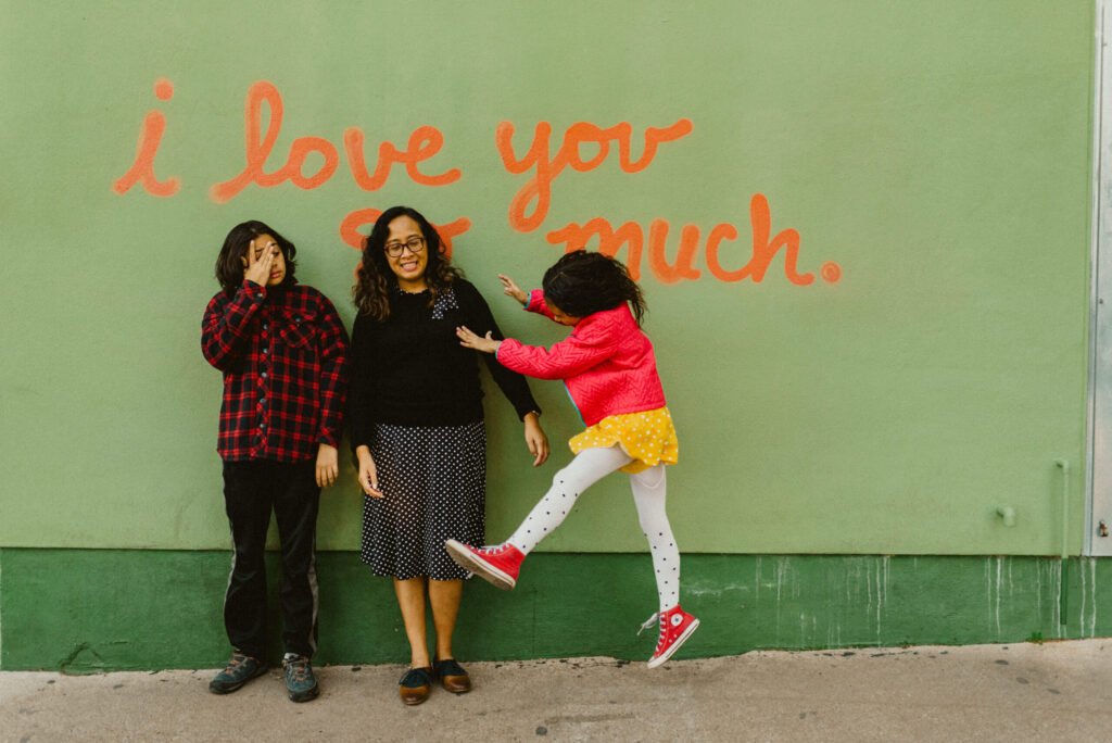 Family posing by 'I love you so much' mural.