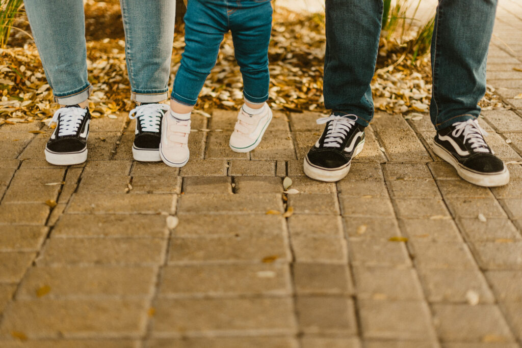 Family wearing sneakers standing on pavement.