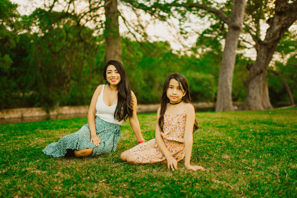 Two people sitting on grass in a park.