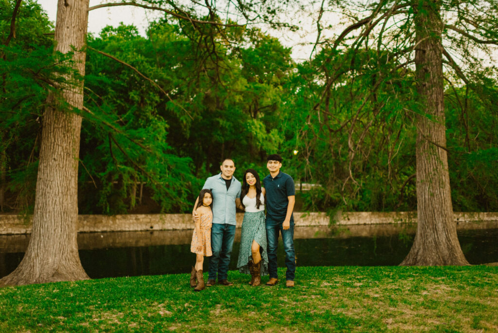 Family posing outdoors in a park setting.