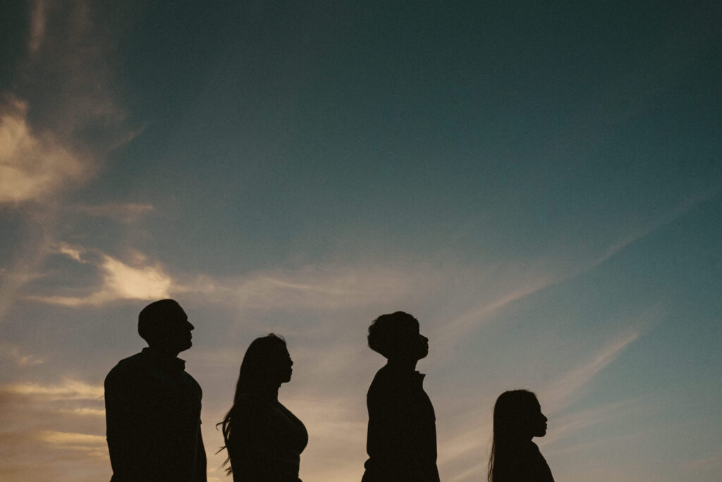 Four silhouettes against sunset sky.