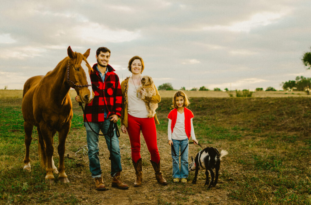 Family with horse, dog, and goat in field