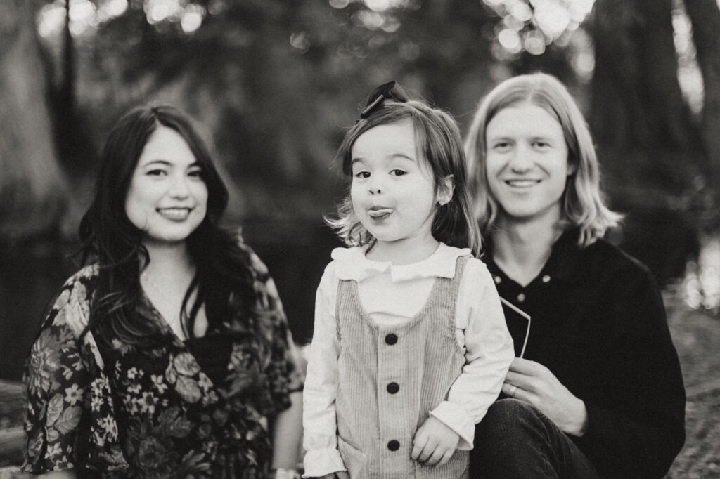 Family portrait with smiling toddler outdoors.