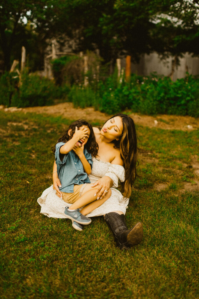 Woman and child playing on grass, pulling funny faces.