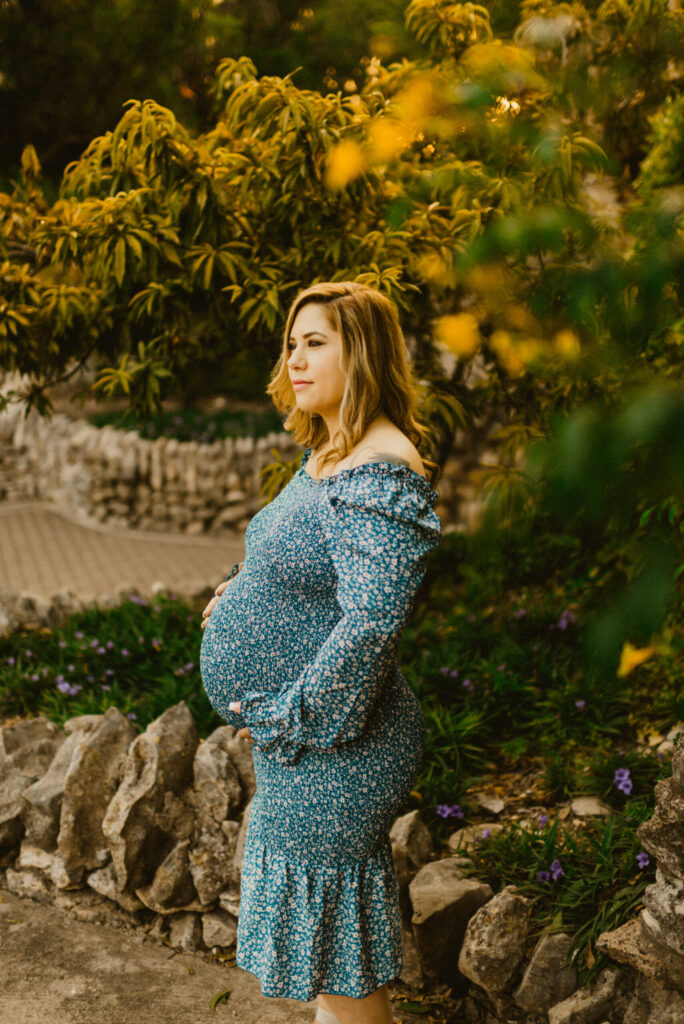 Pregnant woman in floral dress standing outdoors