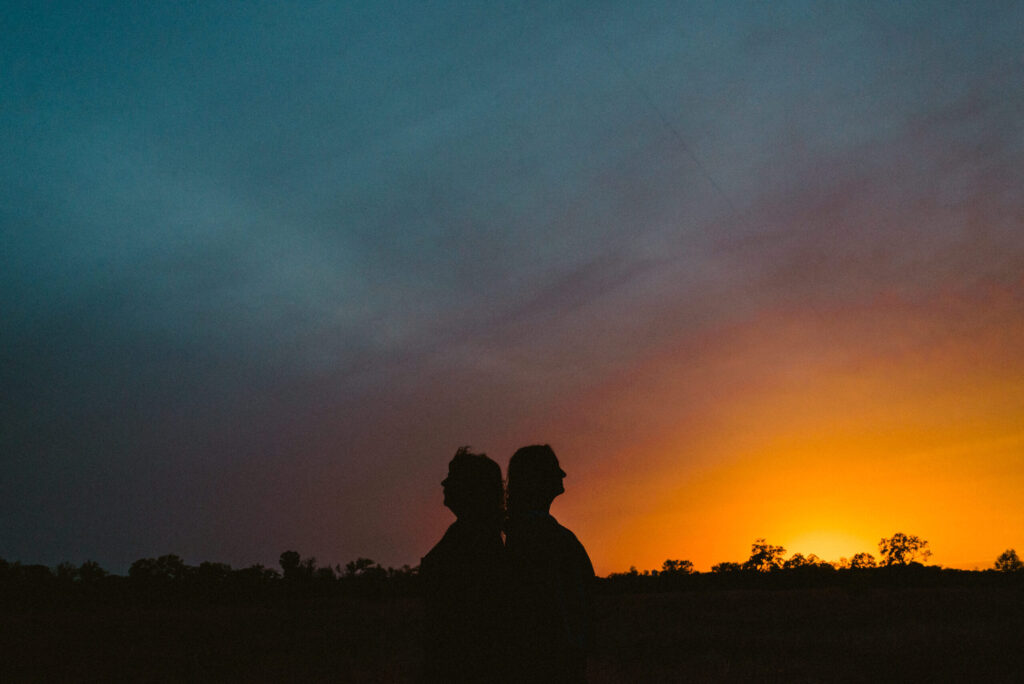 Silhouettes at sunset with colorful sky backdrop.
