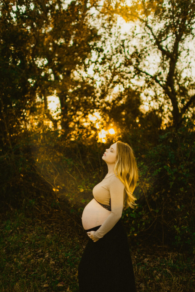 Pregnant woman in nature at sunset.